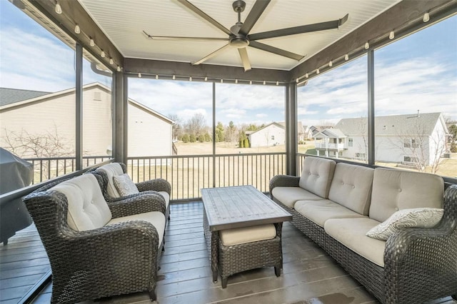 sunroom / solarium with a residential view, a ceiling fan, and a healthy amount of sunlight