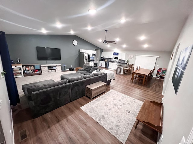 living room with hardwood / wood-style flooring, vaulted ceiling, and ceiling fan