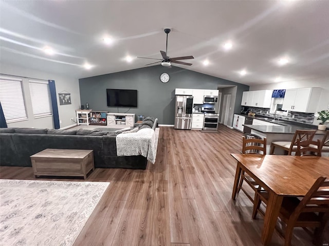 living room with light hardwood / wood-style flooring, ceiling fan, and lofted ceiling