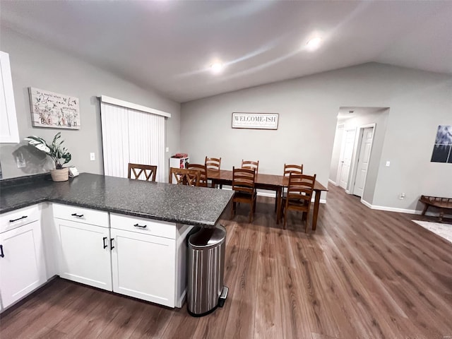 kitchen with kitchen peninsula, dark hardwood / wood-style floors, white cabinetry, and lofted ceiling