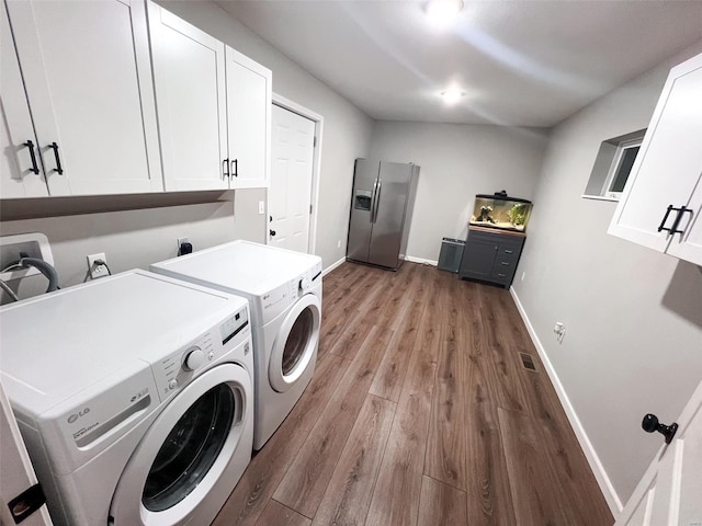 clothes washing area with cabinets, independent washer and dryer, and wood-type flooring