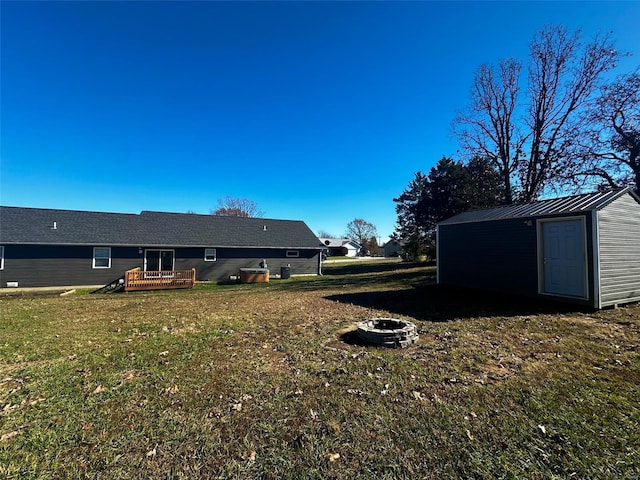 view of yard featuring a wooden deck, a fire pit, and a storage shed