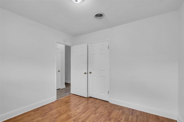 unfurnished bedroom with a closet and light hardwood / wood-style floors