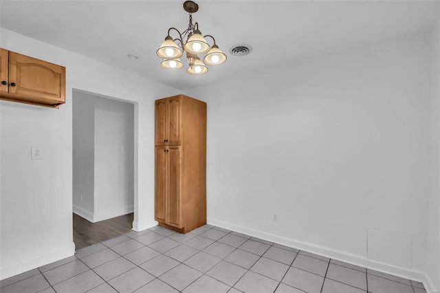 tiled spare room with an inviting chandelier