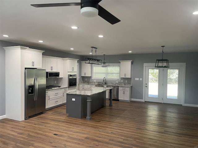 kitchen with a kitchen island, white cabinets, decorative light fixtures, and stainless steel appliances