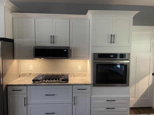 kitchen with tasteful backsplash, white cabinetry, and stainless steel appliances