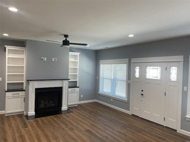 unfurnished living room featuring dark wood-type flooring and ceiling fan