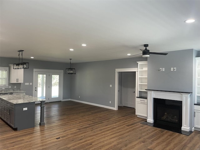 kitchen featuring hanging light fixtures, light stone countertops, dark hardwood / wood-style floors, and white cabinetry