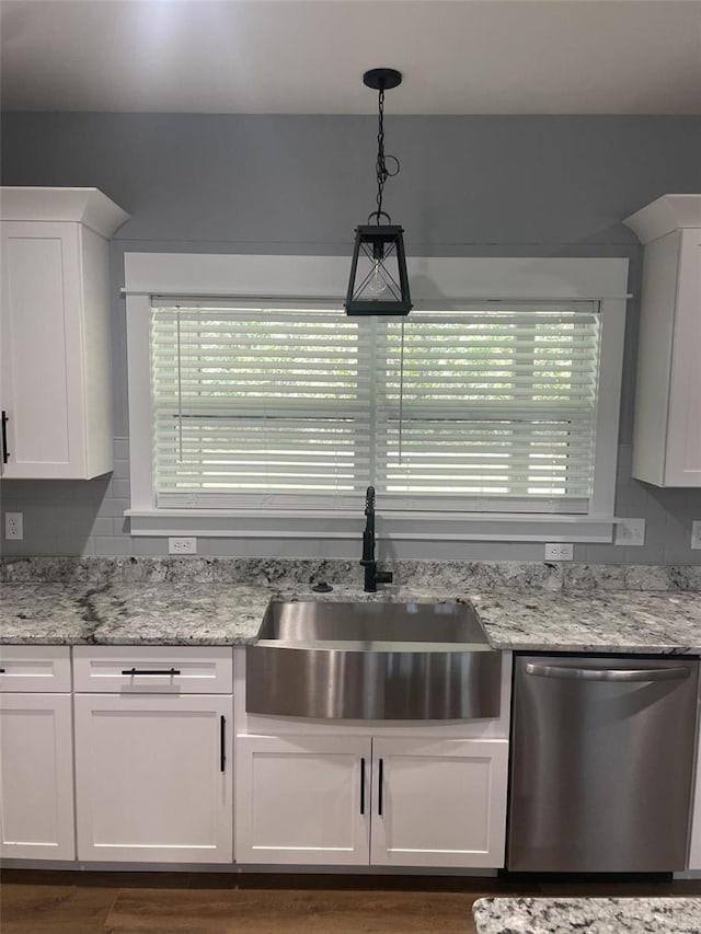 kitchen featuring white cabinetry, sink, light stone counters, decorative light fixtures, and stainless steel dishwasher