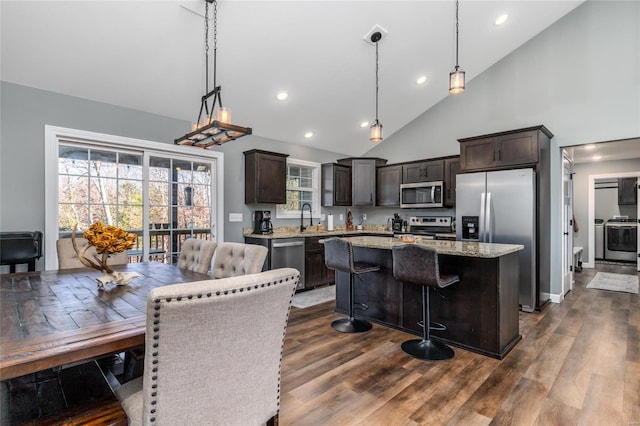 kitchen featuring stainless steel appliances, dark hardwood / wood-style floors, dark brown cabinets, a kitchen island, and pendant lighting