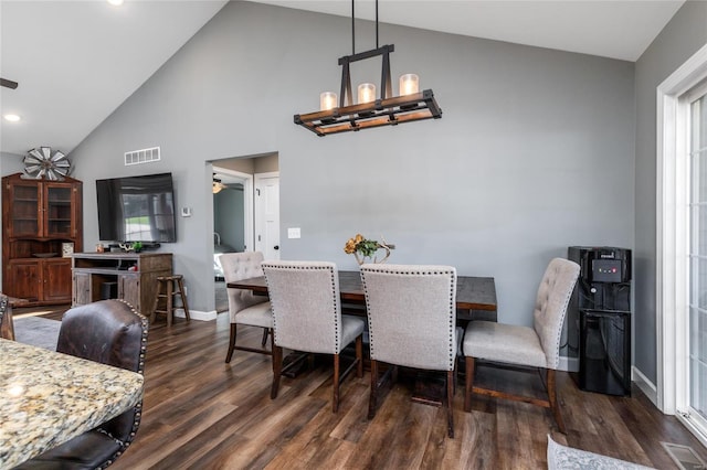 dining room with dark wood-type flooring, high vaulted ceiling, and a notable chandelier