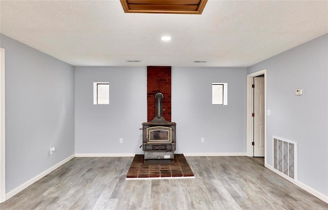 unfurnished living room featuring hardwood / wood-style floors, plenty of natural light, and a wood stove