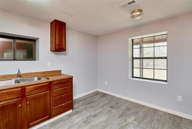 kitchen featuring a textured ceiling, light wood-type flooring, and sink