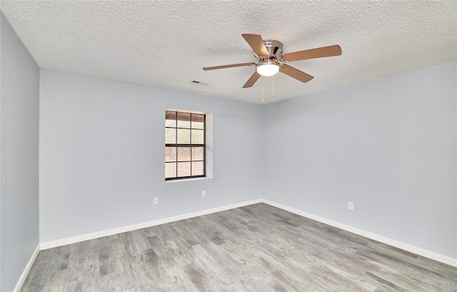 empty room featuring ceiling fan, wood-type flooring, and a textured ceiling