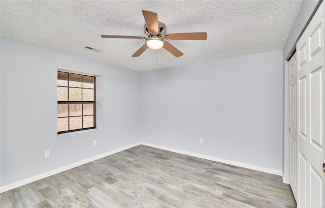 spare room featuring ceiling fan, light hardwood / wood-style floors, and a textured ceiling