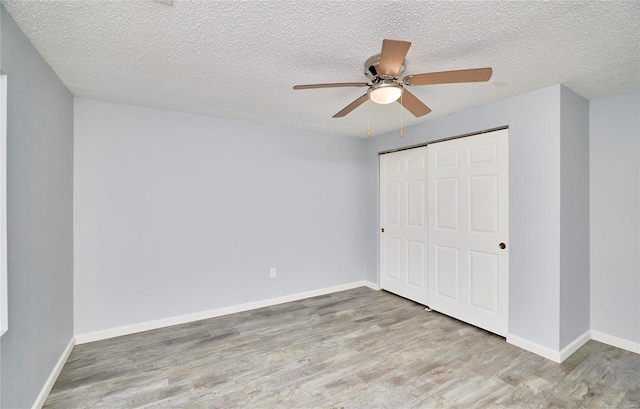 unfurnished bedroom with ceiling fan, a closet, a textured ceiling, and light hardwood / wood-style flooring