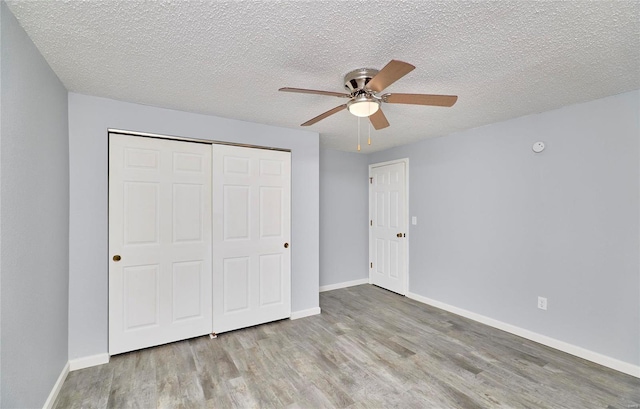 unfurnished bedroom featuring a textured ceiling, light wood-type flooring, a closet, and ceiling fan