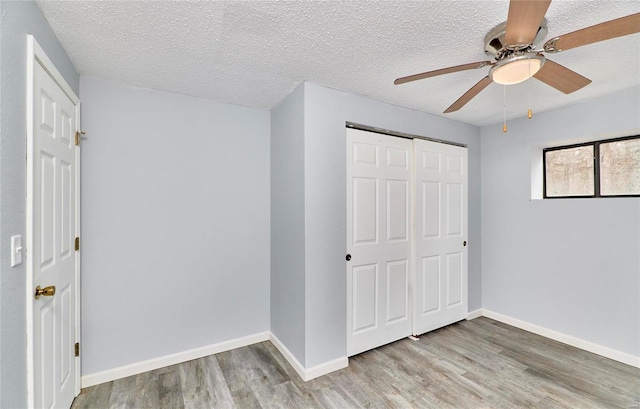 unfurnished bedroom featuring ceiling fan, wood-type flooring, a textured ceiling, and a closet