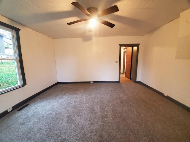 spare room featuring ceiling fan and dark carpet