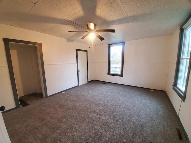 spare room featuring dark colored carpet and ceiling fan