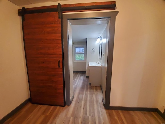 hall with a barn door, light hardwood / wood-style floors, and sink