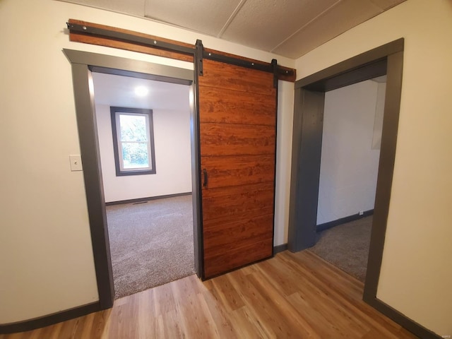 hallway with light carpet and a barn door