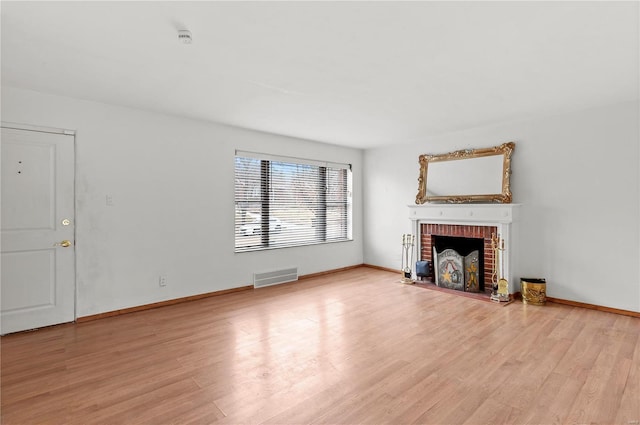 unfurnished living room featuring light hardwood / wood-style flooring and a brick fireplace