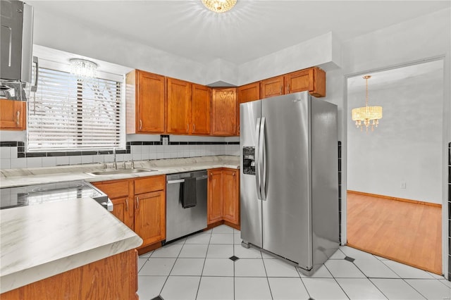 kitchen featuring decorative light fixtures, sink, stainless steel appliances, and a chandelier