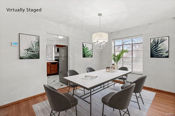 dining area with light hardwood / wood-style floors and an inviting chandelier