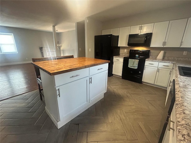 kitchen with white cabinetry, butcher block countertops, black appliances, and dark parquet flooring