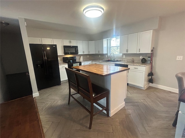 kitchen featuring white cabinets, black appliances, sink, parquet floors, and a kitchen island