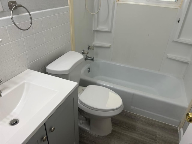 full bathroom featuring tile walls, wood-type flooring, toilet, vanity, and bathtub / shower combination