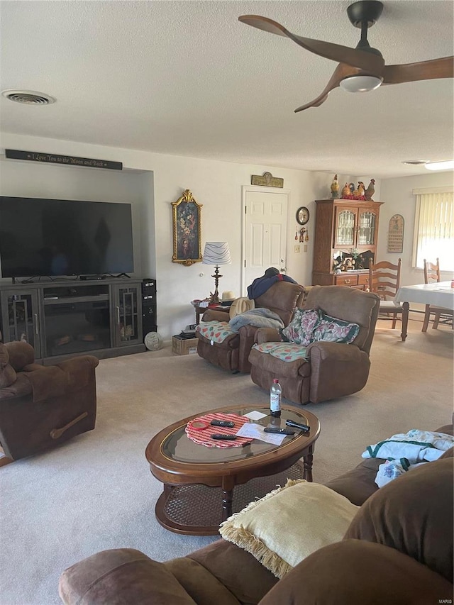 carpeted living room with ceiling fan and a textured ceiling