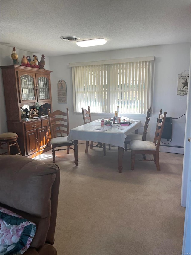 dining area featuring a textured ceiling, light colored carpet, and a baseboard heating unit