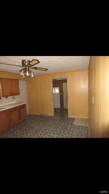 kitchen with ceiling fan and wooden walls