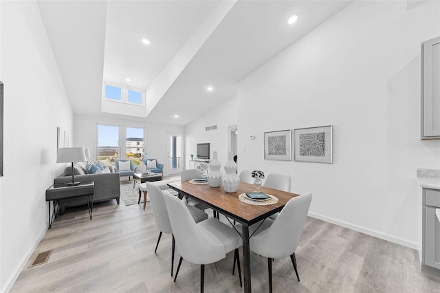 dining room with light hardwood / wood-style floors and high vaulted ceiling