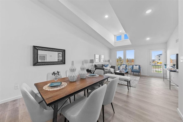 dining space with light hardwood / wood-style flooring and high vaulted ceiling