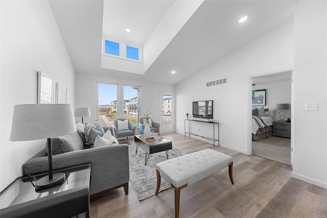 living room featuring high vaulted ceiling and light hardwood / wood-style floors