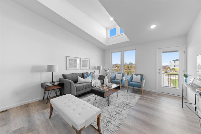 living room featuring high vaulted ceiling and light hardwood / wood-style flooring