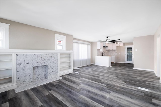 unfurnished living room featuring dark hardwood / wood-style flooring, sink, and ceiling fan