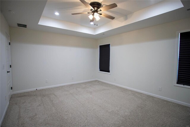 carpeted empty room featuring ceiling fan and a tray ceiling