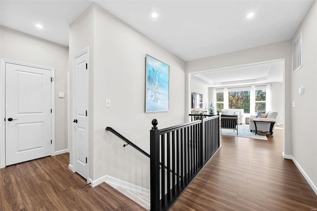 corridor with dark hardwood / wood-style flooring and a tray ceiling