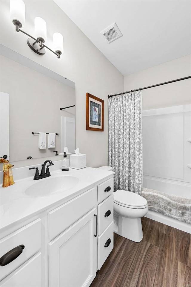 full bathroom featuring wood-type flooring, shower / bath combo with shower curtain, toilet, and vanity