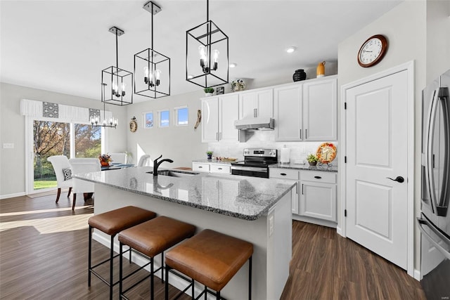 kitchen with dark hardwood / wood-style flooring, white cabinets, sink, appliances with stainless steel finishes, and decorative light fixtures