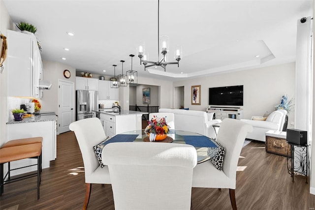 dining area with a chandelier, dark hardwood / wood-style flooring, sink, and a raised ceiling