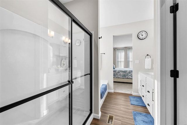 bathroom with wood-type flooring, vanity, and a shower with shower door