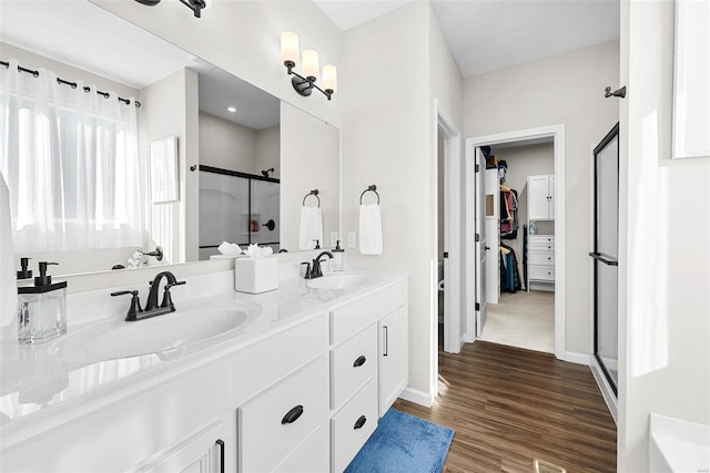 bathroom with hardwood / wood-style floors, a shower with door, and vanity