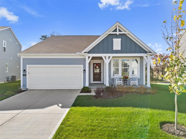 view of front of home with a garage, cooling unit, a front yard, and a porch