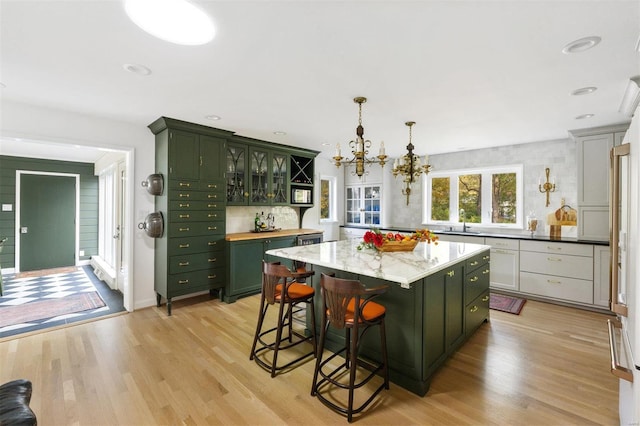 kitchen with a center island, light hardwood / wood-style flooring, hanging light fixtures, and green cabinets