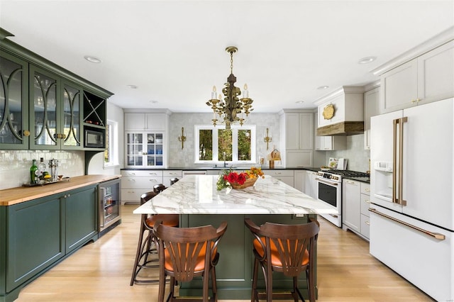 kitchen with green cabinets, white appliances, hanging light fixtures, and wine cooler